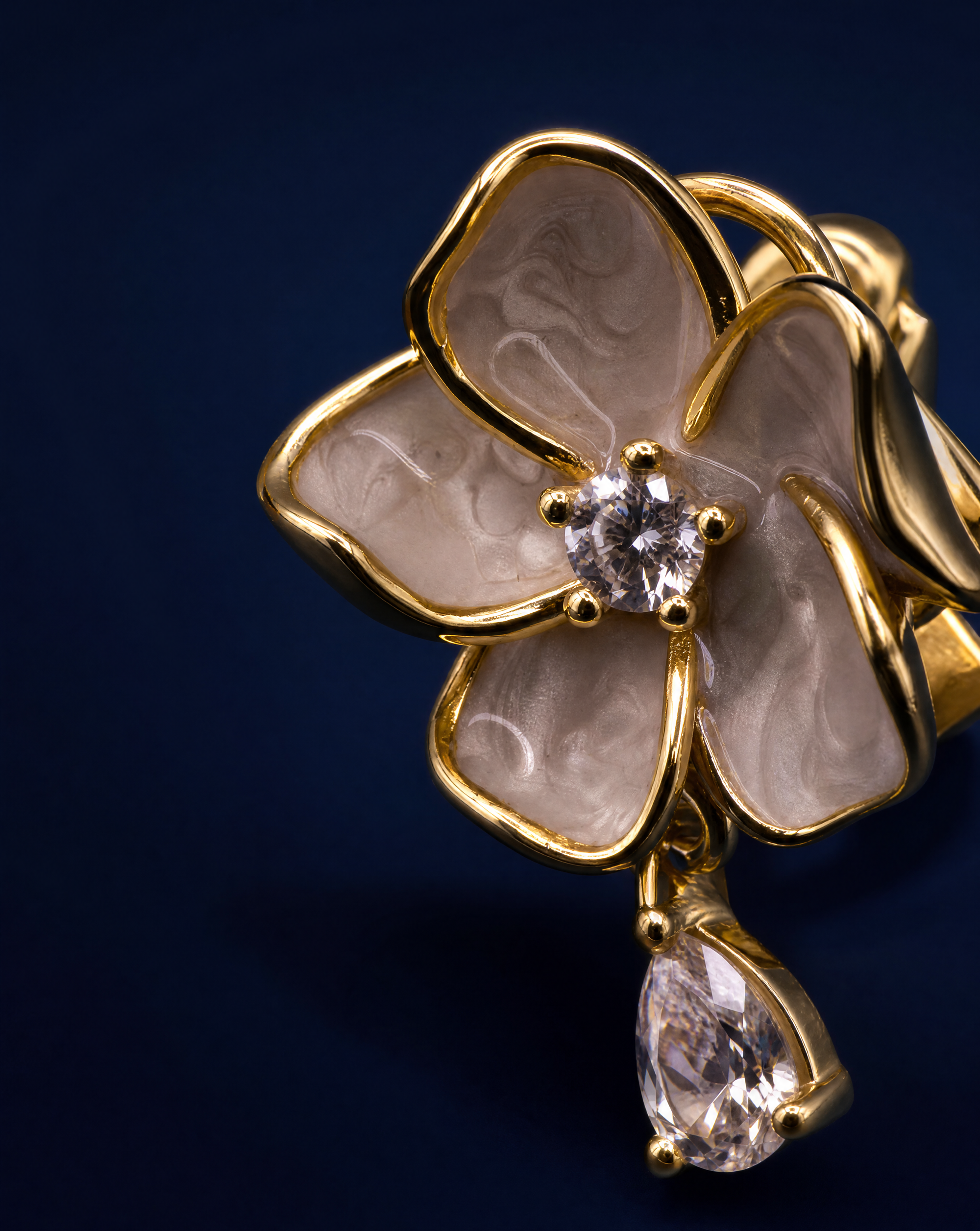 Floral earrings with gold frames, beige centers, and clear gemstones on a white background