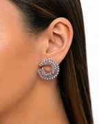 Close-up of a woman's ear wearing a silver earring with a white background