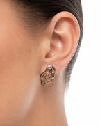 Close-up of an ear wearing a gold earring with a pearl center.