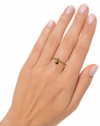 14K Gold ring with small heart charm on a hand against a white background