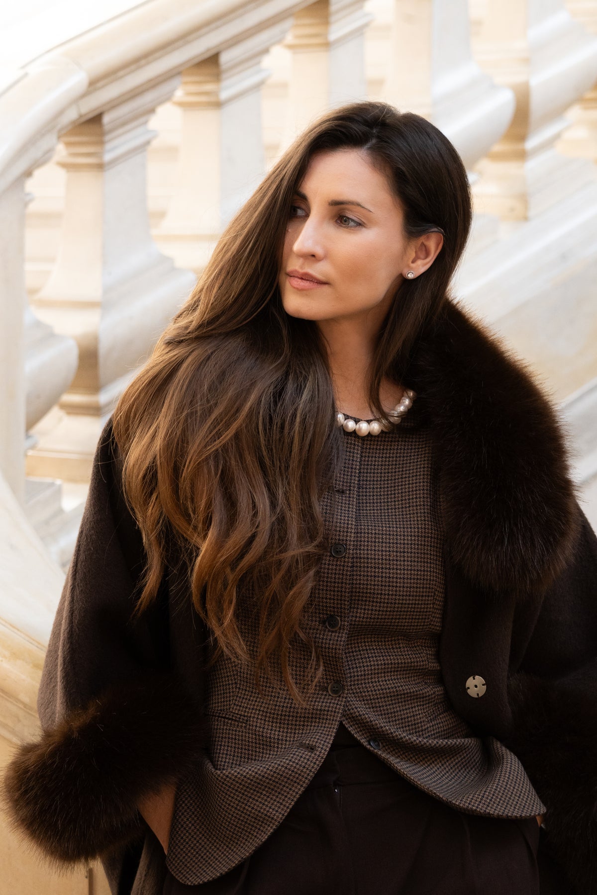 Woman wearing a dark coat with fur trim in an elegant interior setting