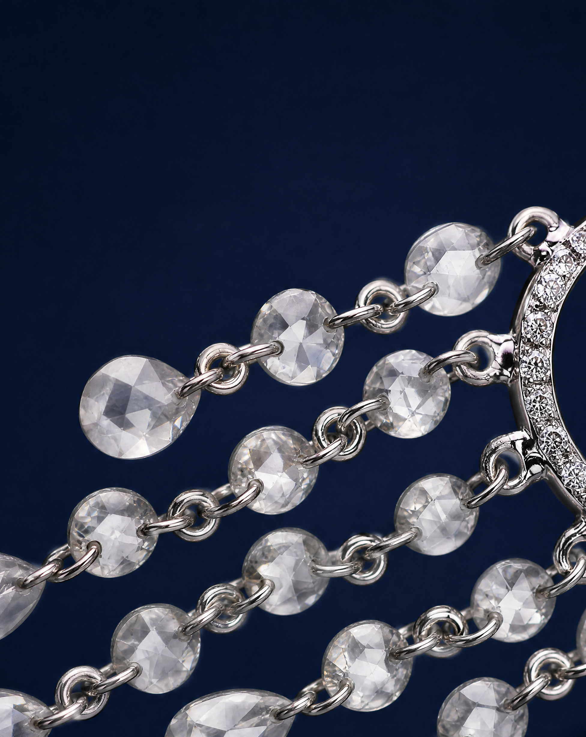 Silver chain with teardrop-shaped pendants on a dark blue background